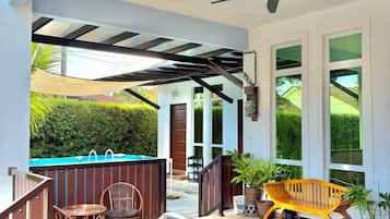 A covered outdoor area with a pool, seating, and potted plants.