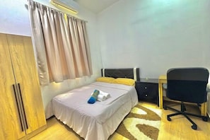 Ein Schlafzimmer mit einem Bett, einem Schreibtisch, einem Stuhl und einem Kleiderschrank.