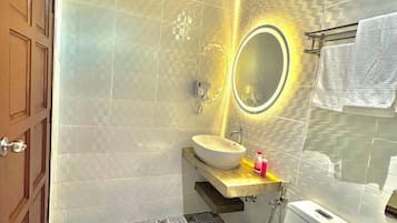 A bathroom with a wooden door, a white sink, a mirror with a light, and a towel rack.