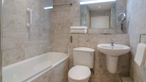 A bathroom with a bathtub, two toilets, a sink, and a mirror. - Deluxe Apartment at Central Belfast Apartments (Belfast)