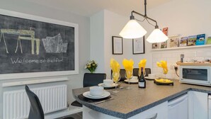 A modern kitchen with a granite countertop, white cabinetry, and a chalkboard wall with "Welcome to Belfast" written on it. - Deluxe Apartment at Central Belfast Apartments (Belfast)