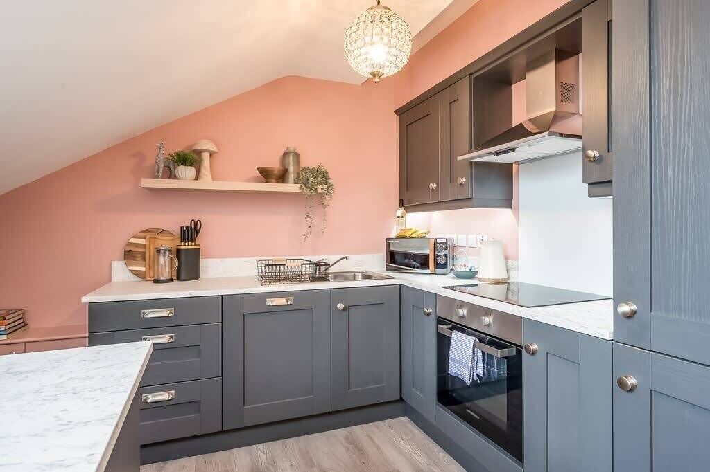 A modern kitchen with grey cabinets, a white countertop, and a built-in oven.