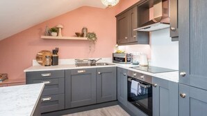 Une cuisine moderne avec des meubles gris, un plan de travail blanc et un four encastré.