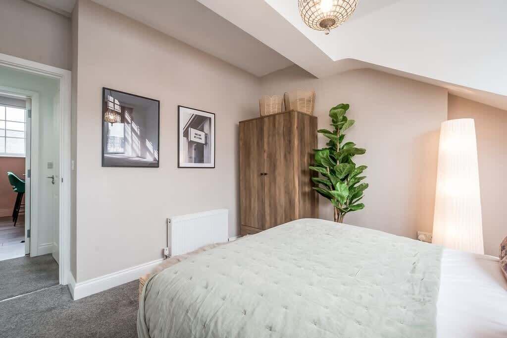 A bedroom with a large bed, a wooden wardrobe, a radiator, and two framed pictures on the wall.