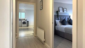 Un appartement moderne avec un couloir menant à une chambre et à un espace cuisine.