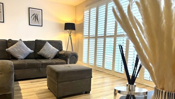 Un salon moderne avec un canapé, un pouf et une lampe sur pied.