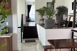 A modern kitchen with a dining area, a staircase, and a large potted plant. - Kim’s House Entire Villa 6-BR Near My Khe Beach (Da Nang)