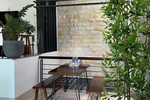 A balcony with a stone wall, a table with benches, and a potted plant. - Kim’s House Entire Villa 6-BR Near My Khe Beach (Da Nang)