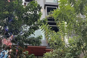 A modern building with balconies, surrounded by trees and greenery. - Kim’s House Entire Villa 6-BR Near My Khe Beach (Da Nang)