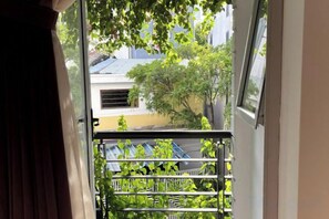 A view through a window with a metal railing, a tree, and a building in the background. - Kim’s House Entire Villa 6-BR Near My Khe Beach (Da Nang)