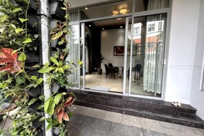 A modern building entrance with a glass door, a staircase, and a dining area visible through the door. - Kim’s House Entire Villa 6-BR Near My Khe Beach (Da Nang)