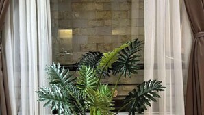A room with a stone wall, sheer curtains, and a potted plant. - Kim’s House Entire Villa 6-BR Near My Khe Beach (Da Nang)