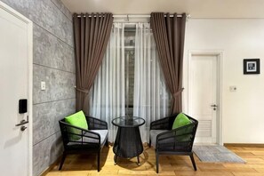 A room with two wicker chairs, a small round table, a door, and a window with curtains. - Kim’s House Entire Villa 6-BR Near My Khe Beach (Da Nang)