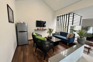 A compact living space with a kitchenette, a sofa, a dining table, and a TV mounted on the wall. - Kim’s House Entire Villa 6-BR Near My Khe Beach (Da Nang)