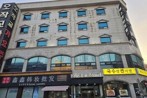 A multi-story building with various storefronts on the ground floor, including a Korean cosmetics store and a restaurant. - Best in Hotel (Siheung-si)
