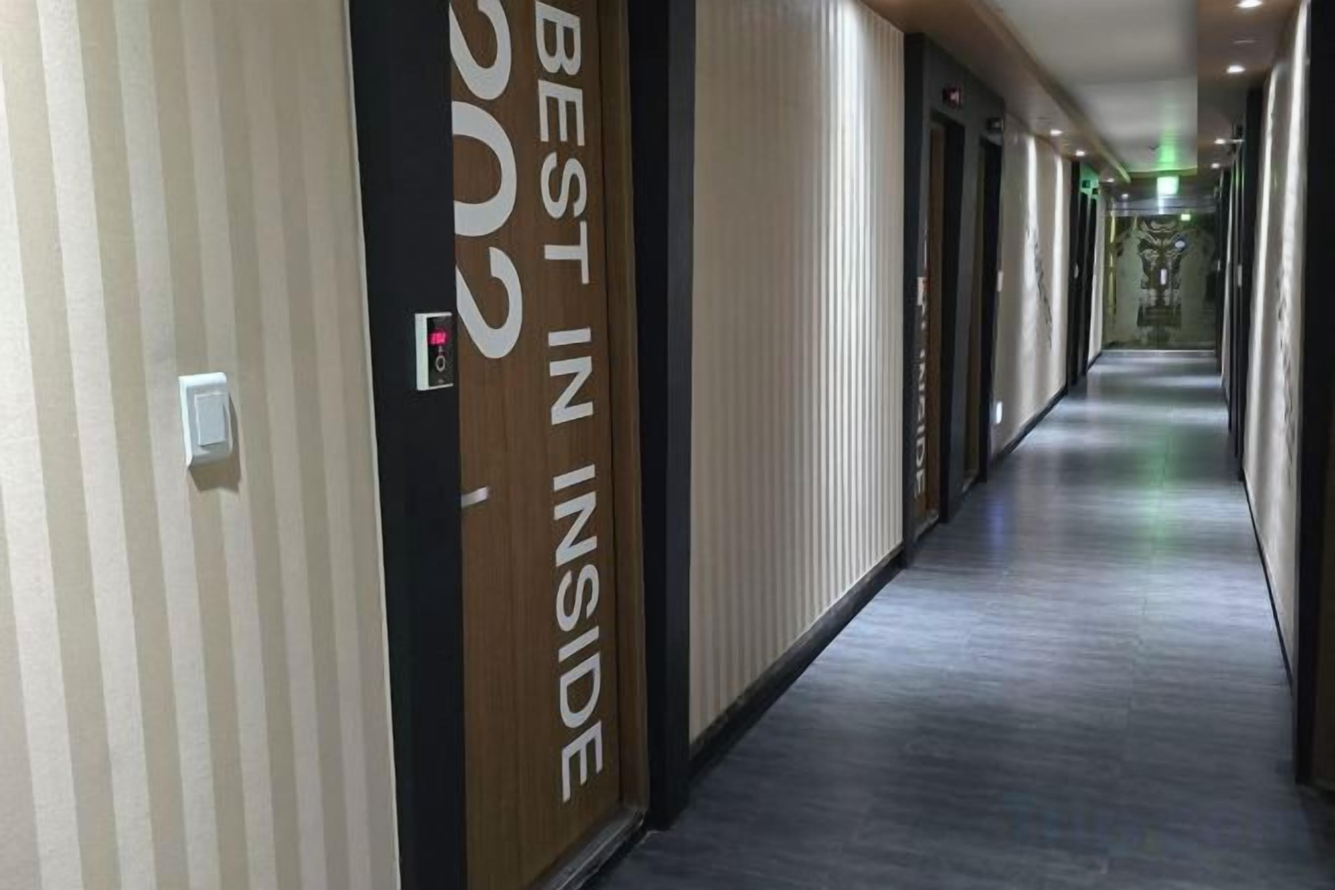 A hotel corridor with a sign reading 'BEST IN INSIDE' and a modern design with a carpeted floor.