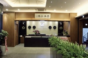 A reception desk with a sign above it, a reception area, and potted plants. - Best in Hotel (Siheung-si)