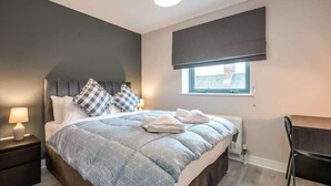 A bedroom with a bed, nightstands, a chair, and a window with a view.