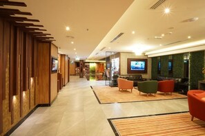 A hotel lobby with a reception desk, seating area, and a television screen. - Concorde Palace Hotel (Dubai)