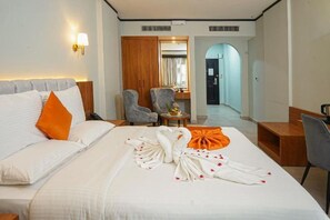 A hotel room with a bed, a desk, a chair, a wardrobe, and a bathroom visible through an archway. - Concorde Palace Hotel (Dubai)