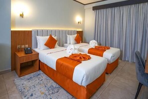 Una camera d'albergo con due letti, un comodino, una sedia e vista sull'esterno.