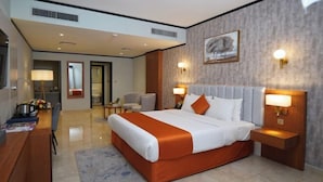 A modern hotel room with a large bed, two bedside tables, a desk, a chair, and a large window. - Concorde Palace Hotel (Dubai)