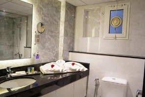 Un baño con un espejo grande, un lavabo, un inodoro y una toalla decorada con corazones.