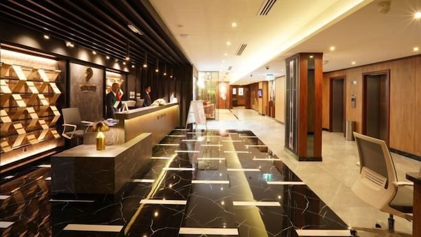 A hotel lobby with a reception desk, seating area, and a modern design with marble flooring and wooden accents. - Concorde Palace Hotel (Dubai)