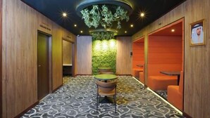 A hallway with a patterned carpet, wooden walls, a green wall with lights, and a luggage room. - Concorde Palace Hotel (Dubai)