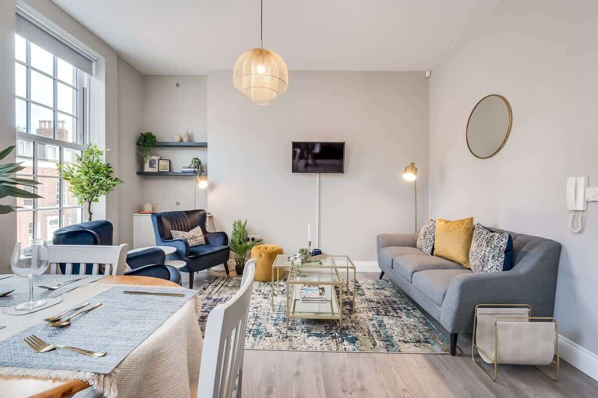 A modern living room with a dining area, a sofa, a TV, and a large window.
