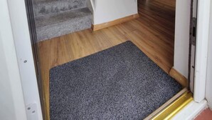 A staircase leading to a room with a wooden floor and a grey carpet at the bottom.
