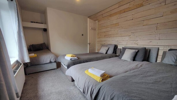 A room with two beds, a sofa, and a wooden wall.