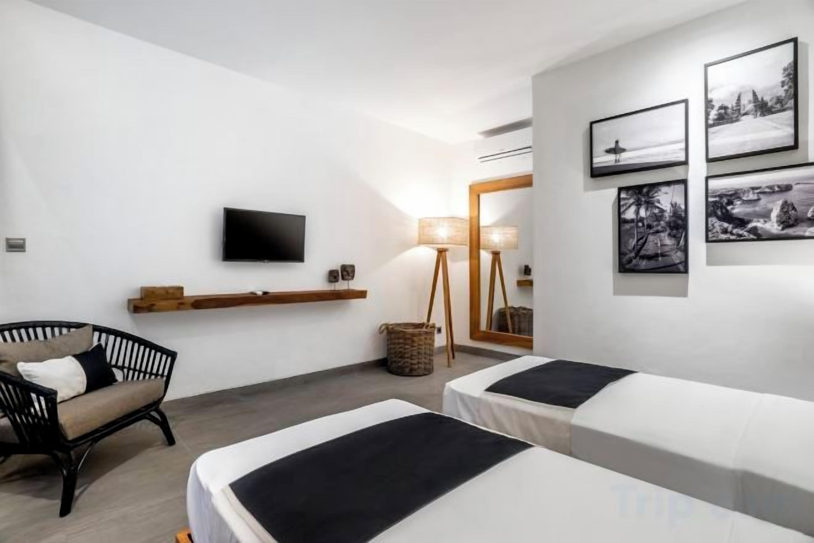 A hotel room with two beds, a TV, a lamp, and a wall-mounted shelf.