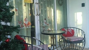 A glass door with festive decorations, a small round table, and a chair with a red cushion. - Your House kkn. (Khon Kaen)