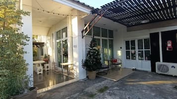 A covered outdoor area with a pergola, a Christmas tree, and a seating area with tables and chairs.