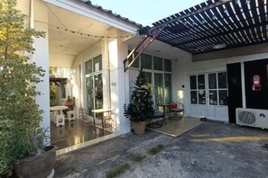A covered outdoor area with a pergola, a Christmas tree, and a seating area with tables and chairs. - Your House kkn. (Khon Kaen)
