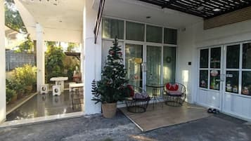 A covered outdoor area with a Christmas tree, seating, and a garage door.
