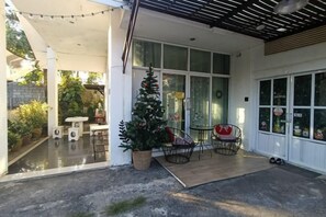 A covered outdoor area with a Christmas tree, seating, and a garage door. - Your House kkn. (Khon Kaen)
