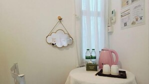 A small room with a round table covered with a white tablecloth, a pink kettle, two bottles of water, and a box of tissues. - Your House kkn. (Khon Kaen)