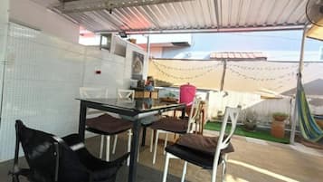 An outdoor patio area with a table and chairs, a fan, and a covered seating area.