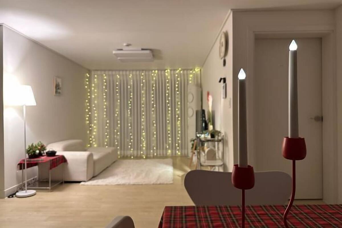 A modern living room with a sofa, a coffee table, a lamp, and a decorative wall with string lights.