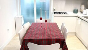 A dining area with a red plaid tablecloth, white chairs, and two red candles. - Aurora Gyeongju (Gyeongju)