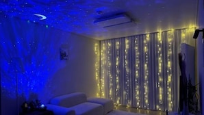 A room with a white sofa, a ceiling projector, and string lights. - Aurora Gyeongju (Gyeongju)