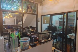 A room with a desk, a fish tank, and a window with a view of a tree. - Panda Lodge Home Stay (Bangkok)
