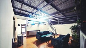 Una habitación con techo de madera, un sofá, una mesa y una escalera.