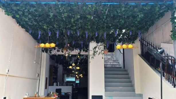 Un interior con escaleras, mesas de madera y plantas colgantes.