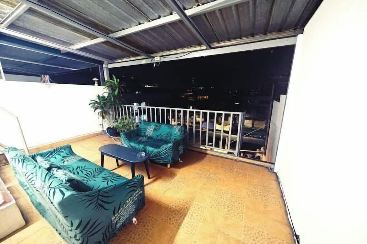 An outdoor seating area with a sofa and a bench, a railing, and a potted plant.