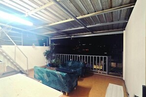A covered outdoor area with a staircase, a sofa, and a railing. - Panda Lodge Home Stay (Bangkok)