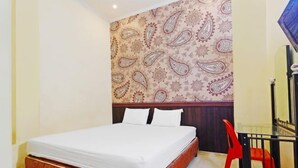 Habitación de hotel con una cama, una silla roja y una pared con estampado de paisley.