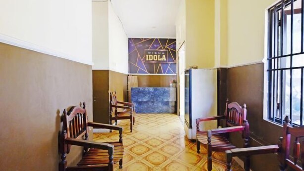 Un vestíbulo de hotel con mostrador de recepción, piso estampado y sillas de madera.